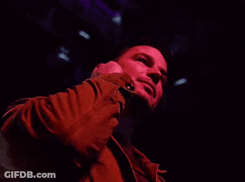 A Man In A Red Jacket Is Covering His Ears With His Hands GIF