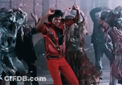 A Man In A Red Jacket Is Dancing With A Group Of Zombies In A Dark Room . GIF