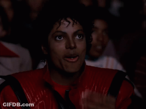 A Man In A Red Jacket Is Eating A Piece Of Popcorn GIF