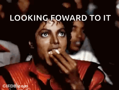 A Man In A Red Jacket Is Eating Popcorn In Front Of A Crowd . GIF
