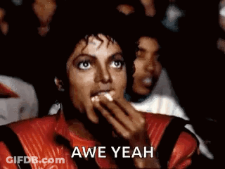 A Man In A Red Jacket Is Eating Popcorn While Watching A Movie In A Theater . GIF