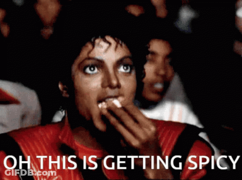 A Man In A Red Jacket Is Eating Popcorn With The Words Oh This Is Getting Spicy Below Him GIF