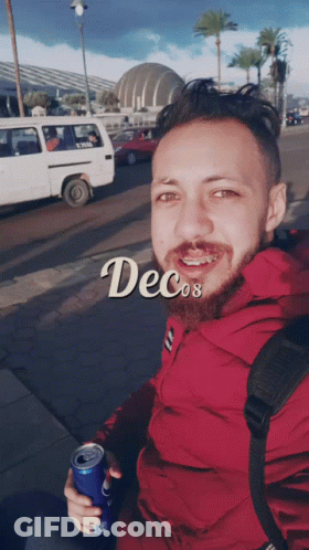 A Man In A Red Jacket Is Holding A Can Of Soda And The Word Decos Is On The Bottom GIF