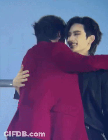 A Man In A Red Jacket Is Hugging Another Man In A Black Jacket . GIF