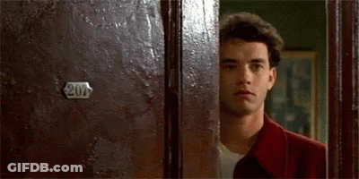 A Man In A Red Jacket Is Peeking Out From Behind A Door . GIF