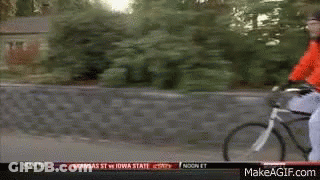A Man In A Red Jacket Is Riding A Bike Down A Street With A Makeagif.com Link In The Corner GIF