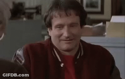 A Man In A Red Jacket Is Sitting At A Table With His Eyes Closed And Smiling . GIF