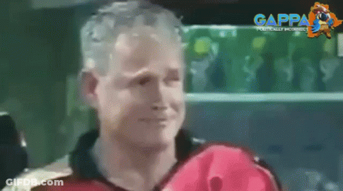 A Man In A Red Jacket Is Smiling In Front Of A Green Shelf With Gappa Written On It GIF
