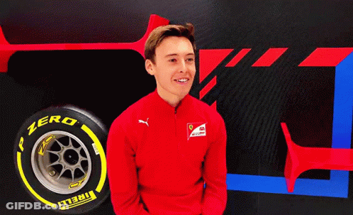 A Man In A Red Jacket Is Smiling In Front Of A Tire That Says Zero On It GIF