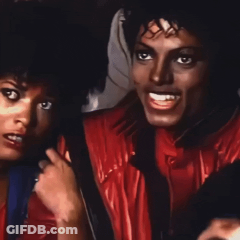 A Man In A Red Jacket Is Smiling Next To A Woman In A Blue Shirt GIF