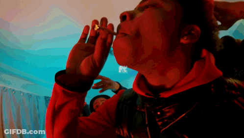 A Man In A Red Jacket Is Smoking A Cigarette With A Fx Logo Behind Him GIF