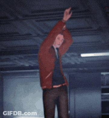 A Man In A Red Jacket Is Standing In A Dark Room With His Hands In The Air GIF