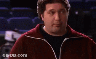 A Man In A Red Jacket Is Standing In Front Of A Sign That Says We . GIF