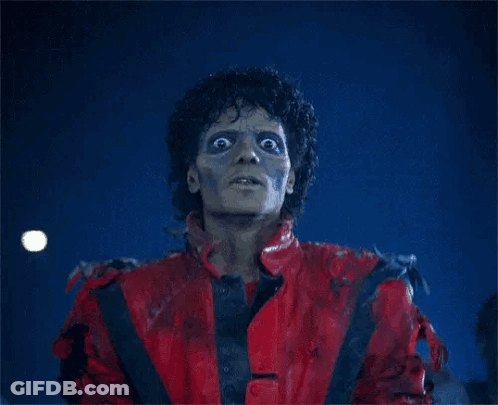 A Man In A Red Jacket Is Standing In Front Of Zombies GIF