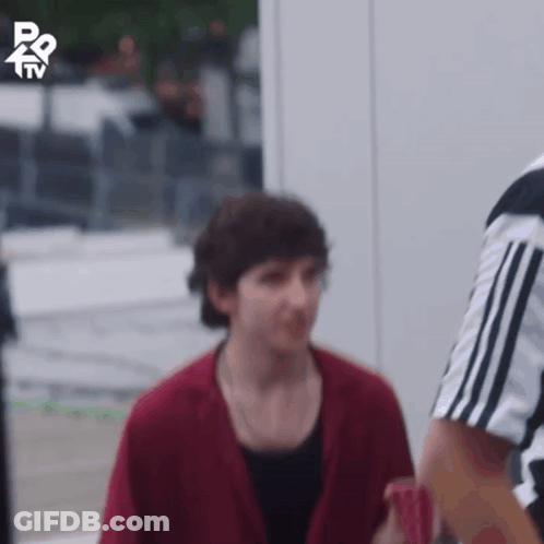 A Man In A Red Jacket Is Standing Next To A Referee In A Black And White Shirt GIF