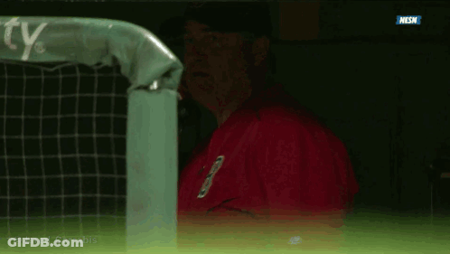 A Man In A Red Jacket Is Talking On A Cell Phone In A Dugout GIF