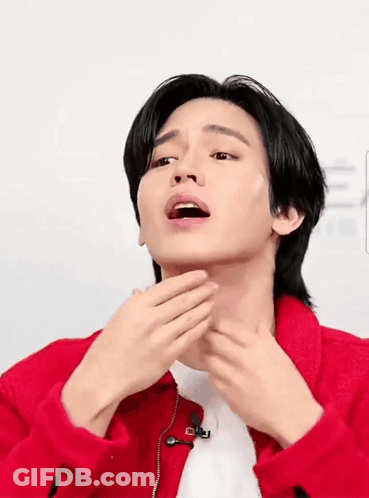 A Man In A Red Jacket Is Touching His Face GIF