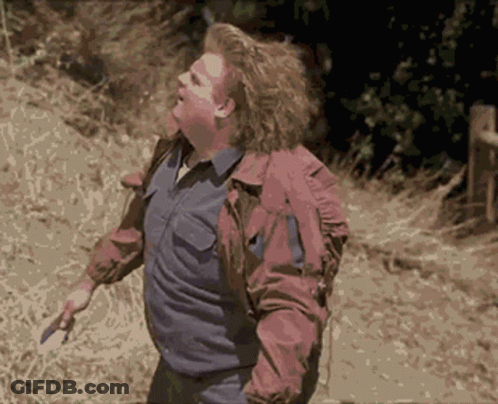 A Man In A Red Jacket Is Walking Down A Dirt Road GIF