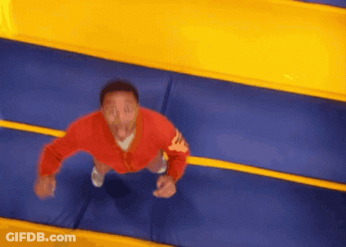 A Man In A Red Jacket Jumps On A Trampoline GIF