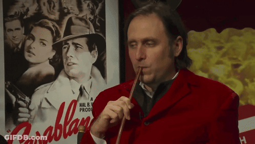 A Man In A Red Jacket Playing A Violin In Front Of A Poster For Parablan GIF