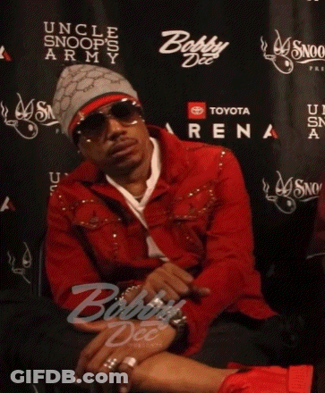 A Man In A Red Jacket Sits In Front Of A Wall That Says Toyota Arena GIF