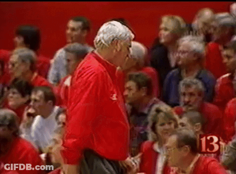 A Man In A Red Jacket Stands In Front Of A Crowd With The Number 13 In The Corner GIF