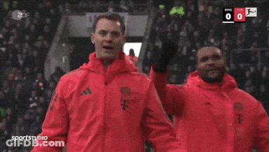A Man In A Red Jacket Stands In Front Of A Scoreboard That Says Sportstudio GIF