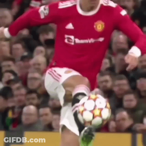 A Man In A Red Jersey Is Kicking A Soccer Ball . GIF