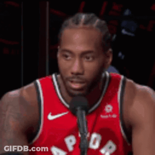 A Man In A Red Jersey Is Talking Into A Microphone . GIF