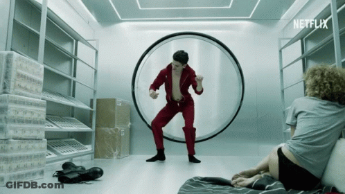 A Man In A Red Jumpsuit Is Dancing In A Room With A Netflix Logo GIF
