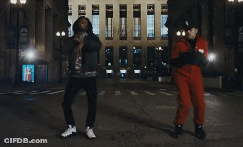 A Man In A Red Jumpsuit Is Dancing With Another Man GIF
