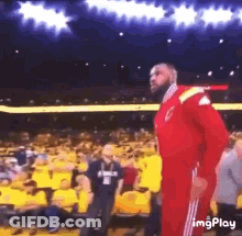 A Man In A Red Jumpsuit Is Standing In Front Of A Crowd Of People . GIF