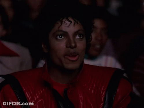 A Man In A Red Leather Jacket Is Clapping His Hands In A Crowd GIF