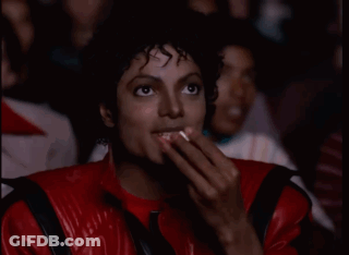 A Man In A Red Leather Jacket Is Covering His Mouth With His Hands GIF