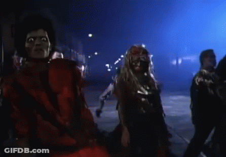 A Man In A Red Mask Is Surrounded By Zombies In A Dark Room GIF