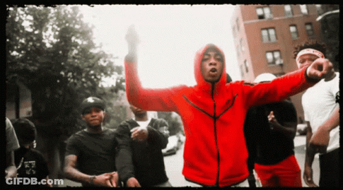 A Man In A Red Nike Jacket Stands In A Crowd Of People GIF