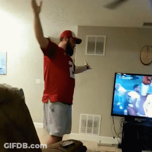 A Man In A Red Number 2 Jersey Stands In Front Of A TV GIF