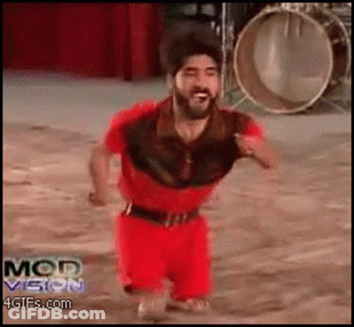 A Man In A Red Outfit Is Running In Front Of A Drum And The Words Mod Vision Are On The Bottom Of The Screen GIF
