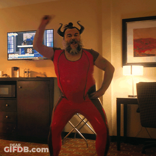 A Man In A Red Outfit With Horns Is Dancing In Front Of A Tv That Says Dear Santa GIF