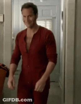 A Man In A Red Pajamas Is Walking Down A Hallway . GIF