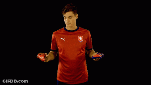 A Man In A Red Puma Shirt Holds Two Soccer Balls GIF