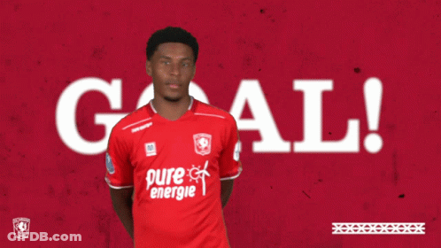 A Man In A Red Pure Energie Shirt Holds His Hands Up In The Air GIF