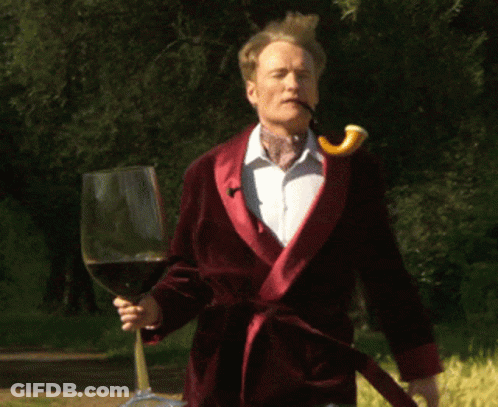 A Man In A Red Robe Holds A Glass Of Wine GIF