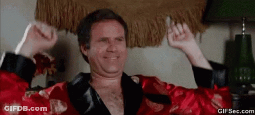 A Man In A Red Robe Is Holding A Cigarette In His Hand And Smiling . GIF