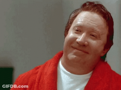 A Man In A Red Robe Is Smiling And Looking At The Camera GIF