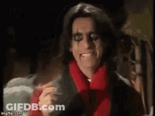 A Man In A Red Scarf Is Smiling And Holding A Cigarette . GIF
