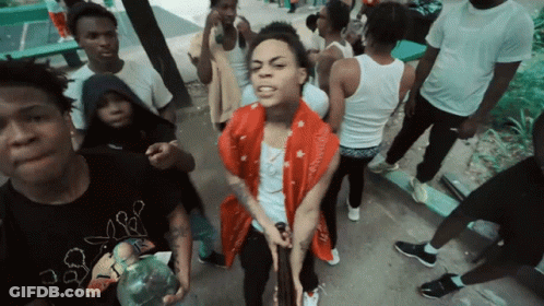 A Man In A Red Scarf Is Surrounded By A Group Of People GIF