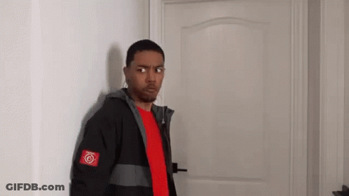 A Man In A Red Shirt And A Black Jacket Is Standing In Front Of A Door . GIF