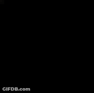 A Man In A Red Shirt And Black Pants Is Standing In Front Of A Tree . GIF