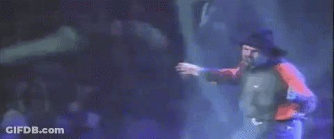 A Man In A Red Shirt And Blue Jeans Is Dancing On A Stage . GIF
